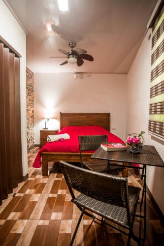 a bedroom with a red bed and a table and chairs at Boutique Hotel Casa Orquídeas in San José