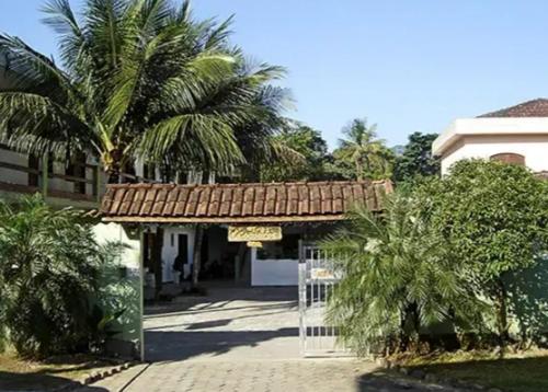un bâtiment avec un portail et des palmiers devant lui dans l'établissement Pousada Recanto 3 Coqueiros, à Boicucanga