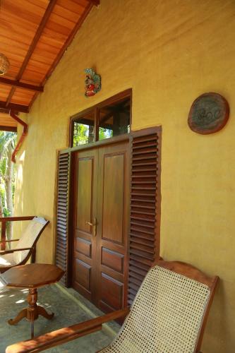 a porch with a door and a table and chairs at Limecabanas-srilanka in Galle