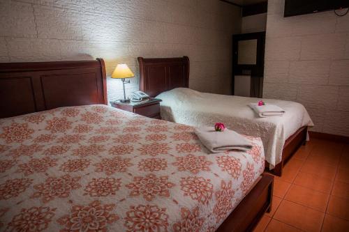 a bedroom with two beds with towels and a lamp at Boutique Hotel Casa Orquídeas in San José