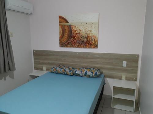 a bed in a room with a painting on the wall at Aldeia do Lago C104- Churrasqueira, bebidas liberadas nas piscinas, internet no ap, rampa no lago, pesqueiro, carregador carro elétrico in Caldas Novas