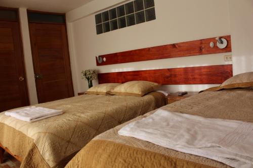 two beds in a hotel room with two beds at Kennedy Guest House in Cusco