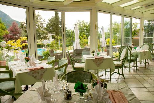 a restaurant with white tables and chairs and windows at Hotel Tiffany in Merano
