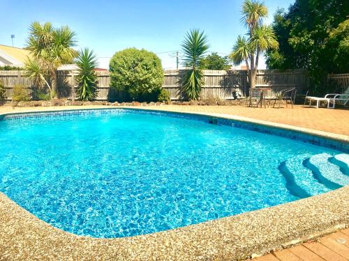 a swimming pool with blue water in a yard at Burwood East Motel in Burwood