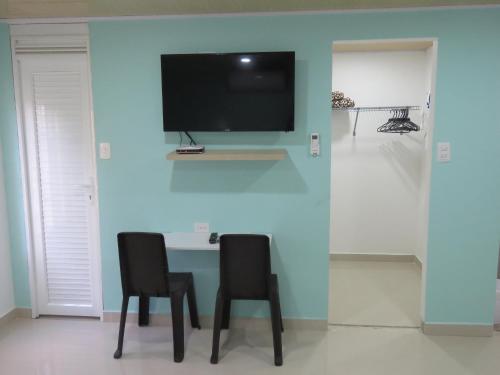 a table with two chairs and a tv on a wall at Posada J&J Forbes - 1 in San Andrés