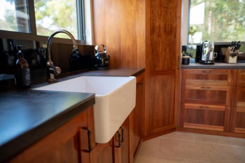 a kitchen with a white sink and wooden cabinets at Adventure Bay Retreat Bruny Island in Adventure Bay