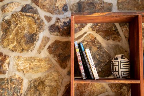 a book shelf with books on it next to a stone wall at Adventure Bay Retreat Bruny Island in Adventure Bay