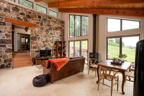 a living room with a stone wall and a couch and a table at Adventure Bay Retreat Bruny Island in Adventure Bay