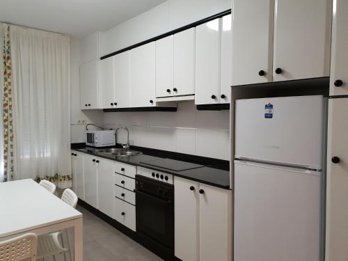 a kitchen with white cabinets and a black and white refrigerator at Cuña Buenavista in Ourense