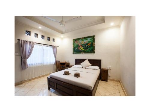 een slaapkamer met een bed en een schilderij aan de muur bij In Da Garden in Ubud