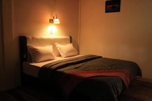 a bedroom with a bed with white pillows and a light at Laster Jony's in Tuk Tuk