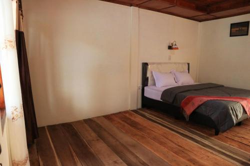 1 dormitorio con 1 cama y suelo de madera en Laster Jony's en Tuk Tuk