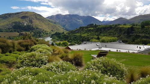 a green field with a building and mountains in the background at Tucker Beach Private Exclusive Retreat in Queenstown