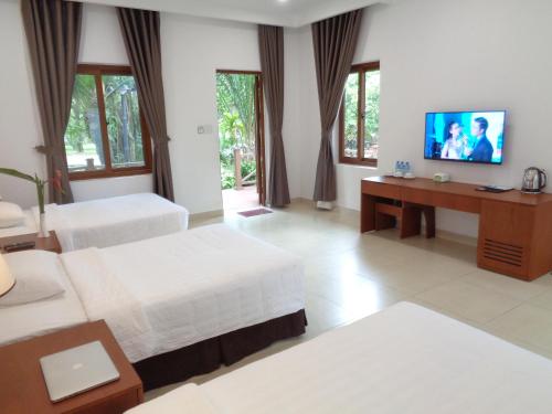 a hotel room with two beds and a flat screen tv at Vuon Xoai Resort in Ấp Phước Cang