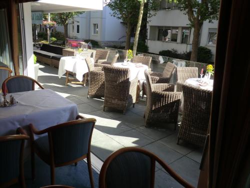a patio with tables and wicker chairs and tablesearcher at Hotel Scherf in Bad Lippspringe