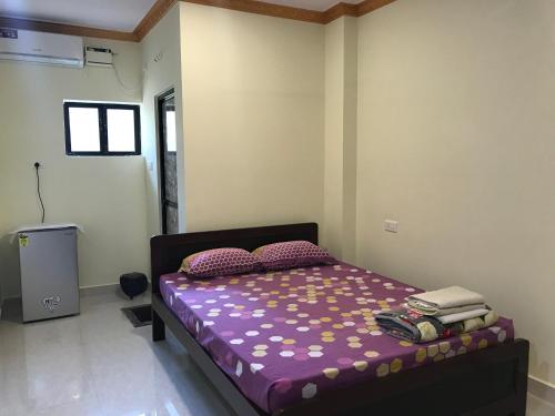 een slaapkamer met een bed met paarse lakens en kussens bij All Seasons Guest House in Vasco Da Gama
