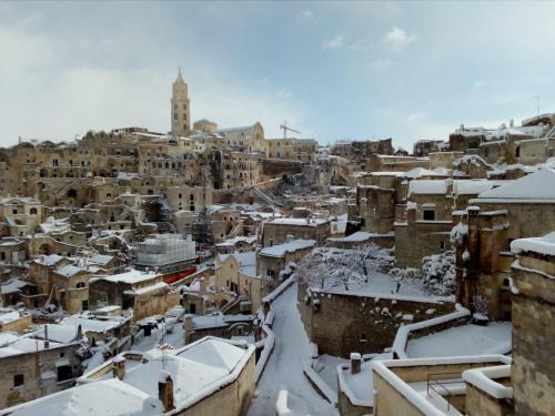 a city covered in snow with a clock tower in the background at L'Affaccio in Matera
