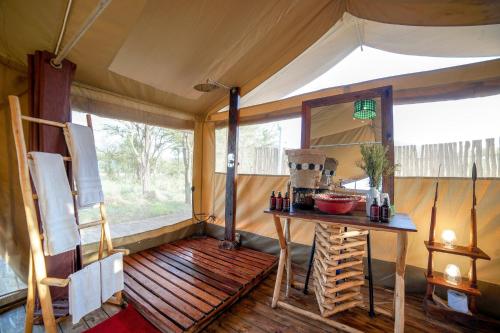 um quarto com uma mesa e um espelho num quarto em Asanja Moru no Parque Nacional de Serengeti