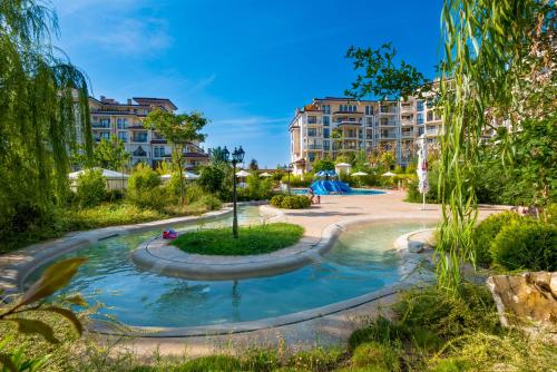 een zwembad in een park met gebouwen op de achtergrond bij Poseidon VIP Residence Club Balneo & SPA Resort in Nesebar