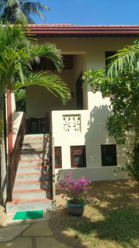a house with stairs and flowers in front of it at Lanka Beach Boutique Bungalows & Grand Villa in Tangalle