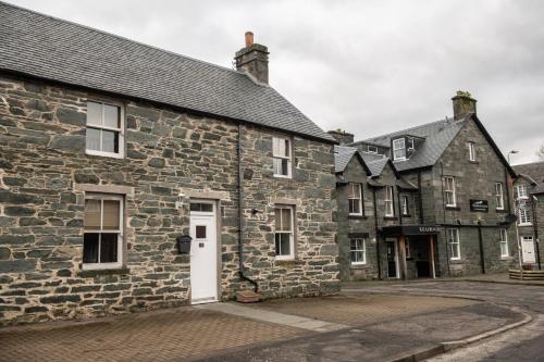 an old stone building with a white door on a street at Old Station Cottages in Aberfeldy