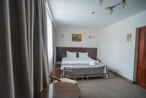 um quarto de hotel com uma cama e uma mesa em Alma em Almaty