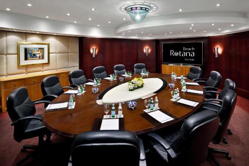 a conference room with a large wooden table and chairs at Beach Rotana – All Suites in Abu Dhabi