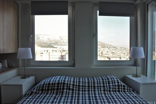 um quarto com duas janelas e uma cama com um cobertor controlado em Xenon Loft em Atenas