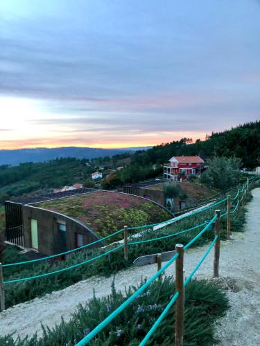 a fence on a hill with a house in the background at Ecofurtado in Furtado