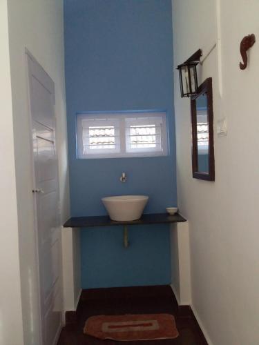 a bathroom with a sink in a blue wall at The First Place Yogaresort, Odayam in Varkala