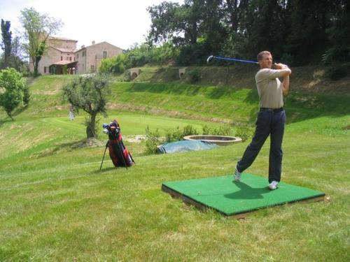 a man swinging a baseball bat on a green field at Castello Montegiove in Fano