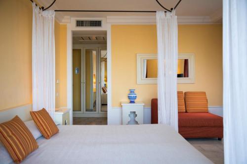 a bedroom with a bed and a red couch at Lu' Hotel Riviera - Carloforte in Carloforte