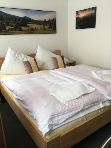 a bed with white sheets and pillows on it at Penzion Na Solné stezce in Kašperské Hory