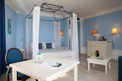 a bedroom with a canopy bed with a white table and a room at Lu' Hotel Riviera - Carloforte in Carloforte