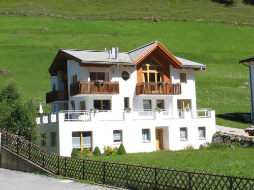 a white house with a balcony on a hill at Apartment MEZPRA in Samnaun