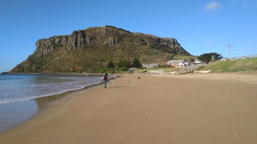 a person walking on a beach with a surfboard at @ the beach & not quite @ the beach Holiday Cottages - Stanley in Stanley