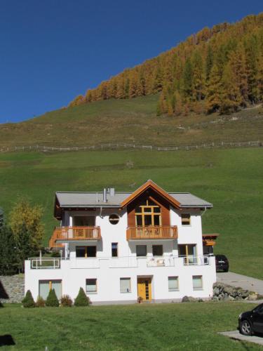 a large white house with a hill in the background at Apartment MEZPRA in Samnaun