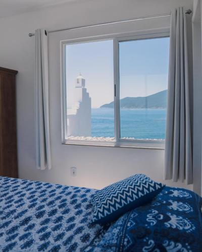 a bedroom with a bed and a large window at Casa Grega in Arraial do Cabo