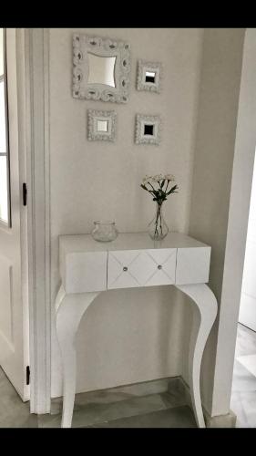 a white console table with a vase of flowers on it at MI CAPRICHO C16 Beachfront Apartment in Mijas Costa