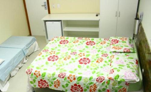 a hospital room with a bed with a flower pattern at Rede Andrade Porto Praia in Porto Seguro
