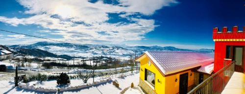 a yellow building in the snow with mountains in the background at Villa Aurora in Villanova del Battista