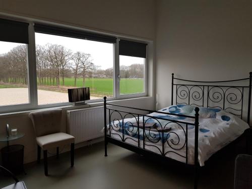 1 dormitorio con cama, ventana y silla en B&B Manege Groenewoude, en Woudenberg