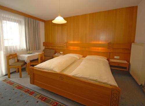 a bedroom with a large bed and a table at Pension Riedlsperger in Saalbach Hinterglemm