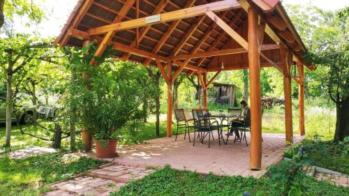 a person sitting under a wooden pavilion in a garden at Cserépmadár szállás és Csinyálóház in Velemér