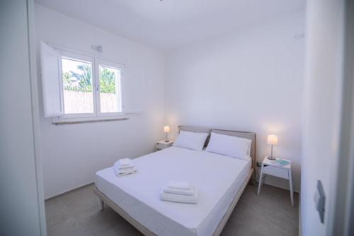 białe łóżko w białym pokoju z oknem w obiekcie Total White Villa w mieście Fontane Bianche