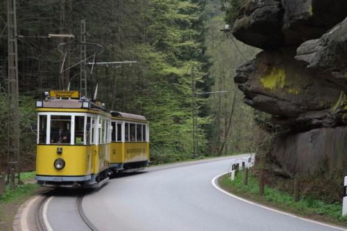 a yellow trolley driving down a road at Restaurant und Pension Zur Puppenstube in Stolpen