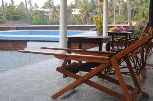 a wooden bench sitting on a patio next to a pool at Magnolia Guesthouse Varkala in Varkala
