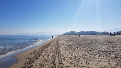 a beach with people walking on the sand and the water at Appartement au Centre de Martil in Martil