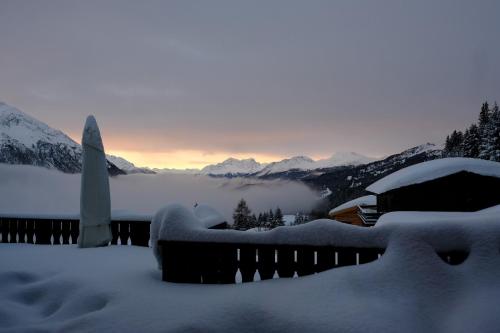 a house covered in snow with mountains in the background at Chalet Casa Cresta - Top of Lenzerheide - bis 8 Personen in Valbella