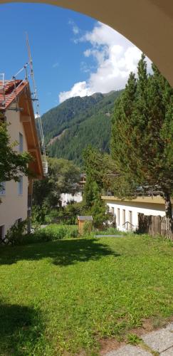 a green yard with a building and mountains in the background at Chasa Melchior in Zernez